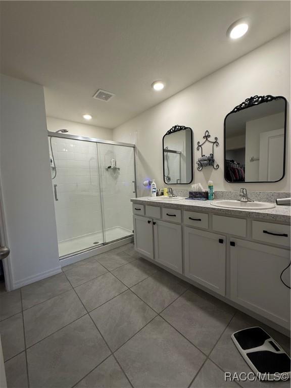bathroom with a shower stall, tile patterned floors, a sink, double vanity, and visible vents