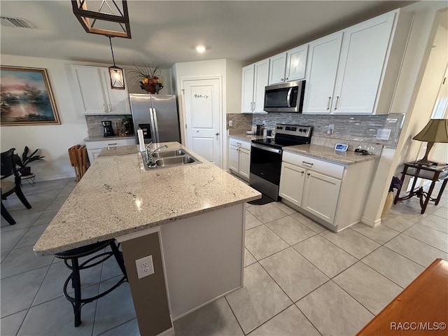 kitchen with a sink, decorative backsplash, light tile patterned flooring, appliances with stainless steel finishes, and visible vents