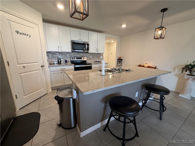 kitchen featuring a sink, light tile patterned floors, white cabinetry, backsplash, and appliances with stainless steel finishes