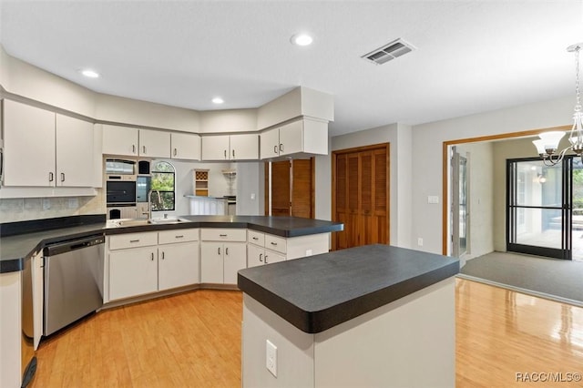 kitchen with white cabinets, dishwasher, and a notable chandelier