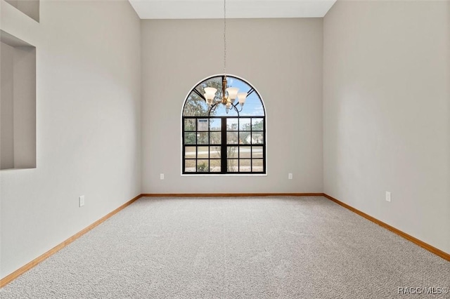 carpeted empty room featuring a chandelier