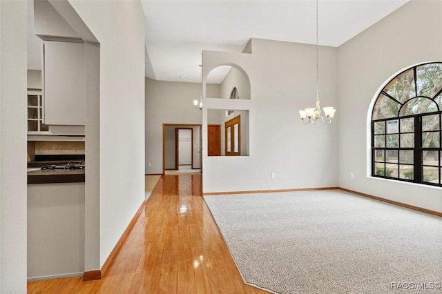 interior space featuring a towering ceiling, light hardwood / wood-style flooring, and an inviting chandelier