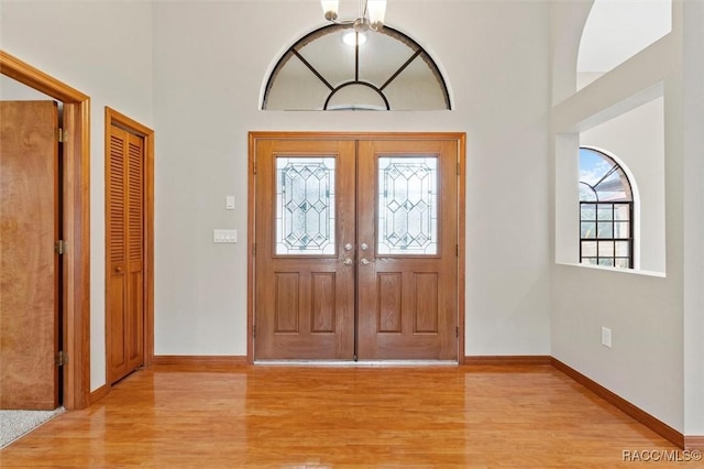 foyer entrance featuring light hardwood / wood-style flooring, a high ceiling, and french doors