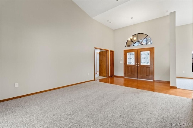 carpeted foyer featuring high vaulted ceiling and a notable chandelier