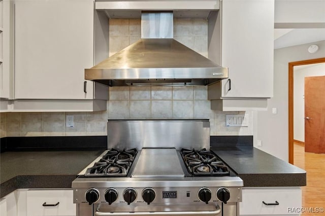 kitchen featuring decorative backsplash, white cabinetry, stainless steel range, and wall chimney exhaust hood