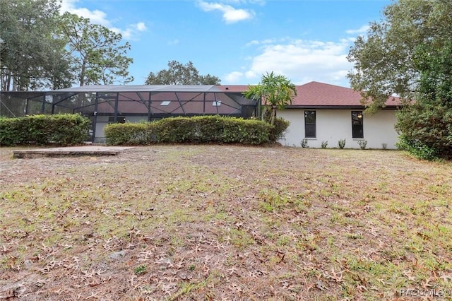 back of property with glass enclosure and a lawn