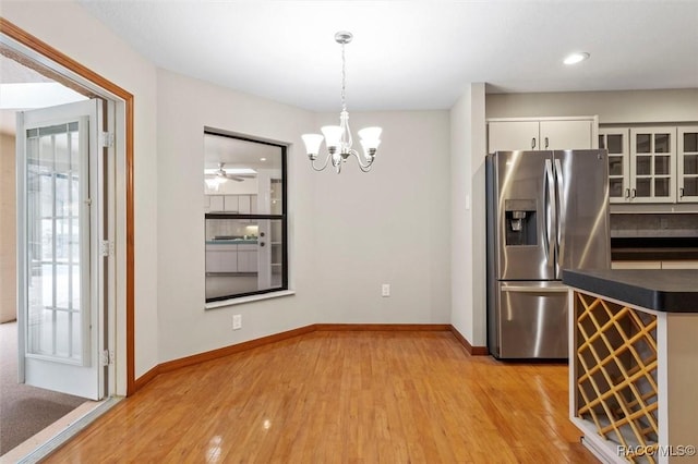 kitchen featuring ceiling fan with notable chandelier, stainless steel refrigerator with ice dispenser, hanging light fixtures, light wood-type flooring, and white cabinetry