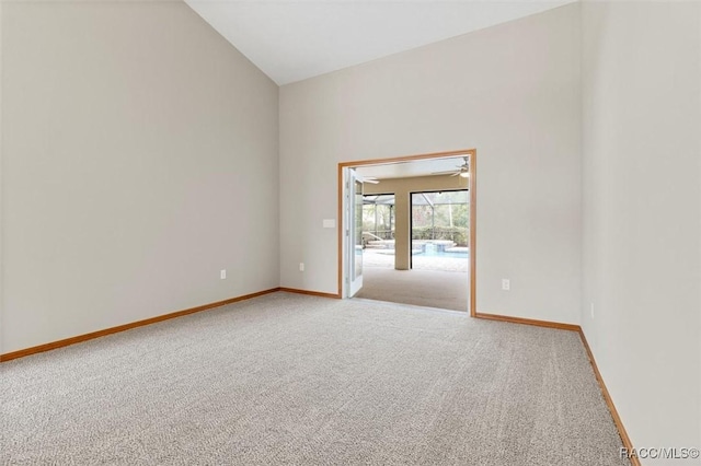 carpeted empty room with high vaulted ceiling