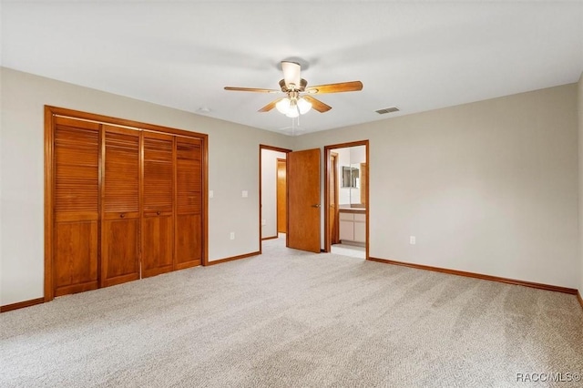 unfurnished bedroom with a closet, ensuite bathroom, ceiling fan, and light colored carpet