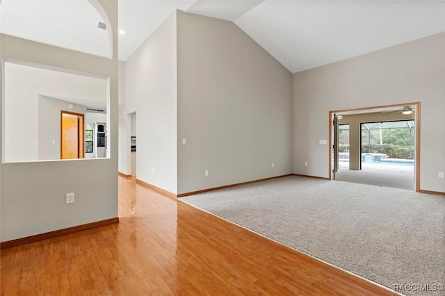 carpeted spare room featuring high vaulted ceiling