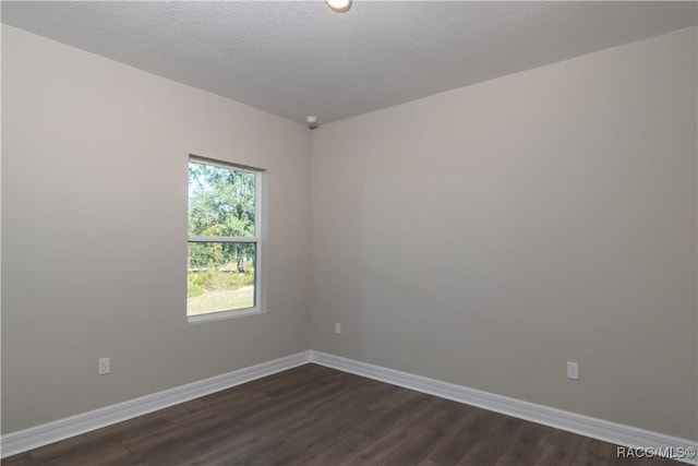 spare room featuring a textured ceiling and dark hardwood / wood-style floors