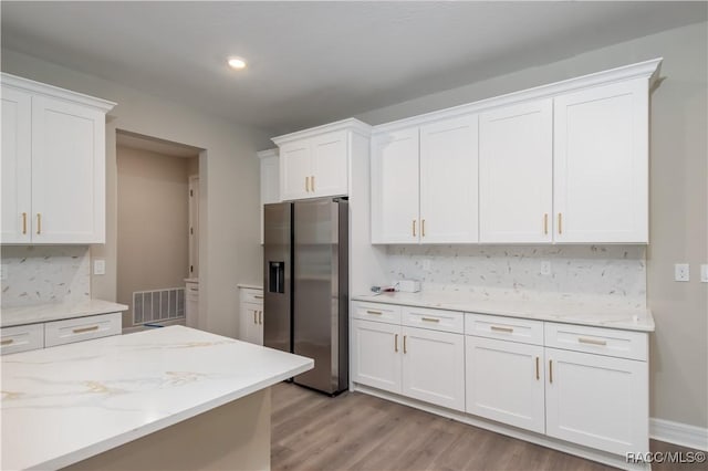 kitchen with white cabinets, tasteful backsplash, stainless steel fridge with ice dispenser, and light hardwood / wood-style flooring