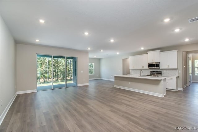 kitchen with stainless steel appliances, sink, a center island with sink, light hardwood / wood-style flooring, and white cabinetry