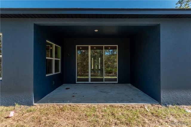 view of exterior entry with a patio