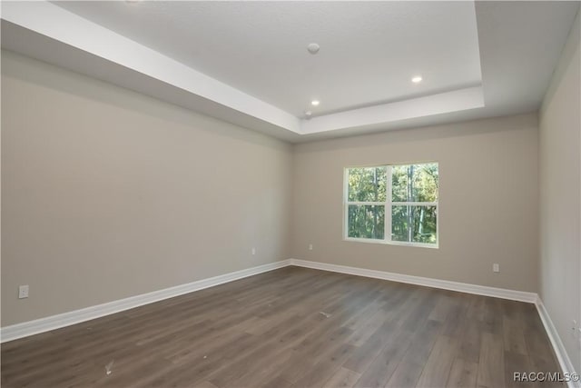 unfurnished room featuring dark hardwood / wood-style floors and a raised ceiling