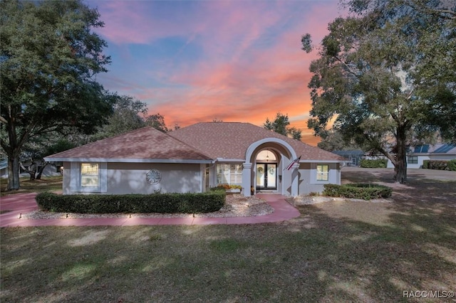 ranch-style home with french doors and a lawn