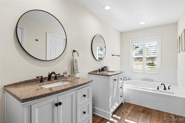 bathroom featuring vanity, wood-type flooring, and tiled bath