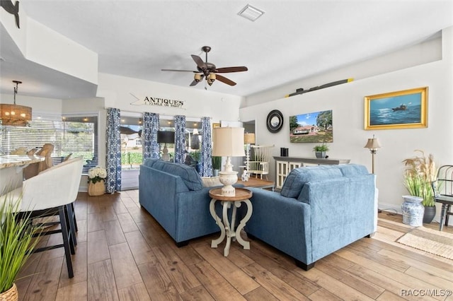 living room featuring ceiling fan with notable chandelier and wood-type flooring