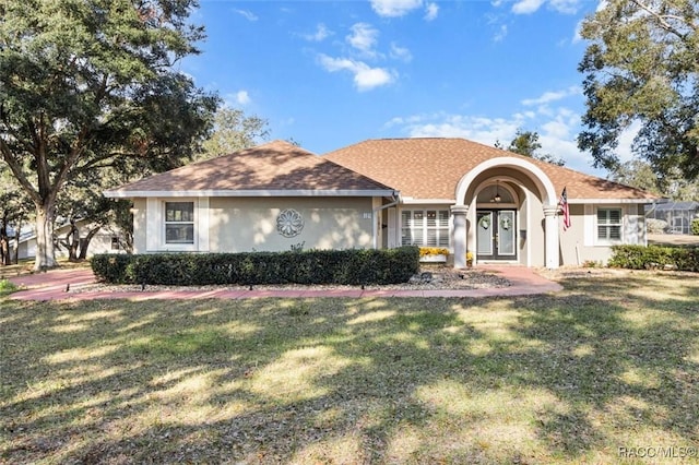 view of front of property with a front lawn, roof with shingles, and stucco siding