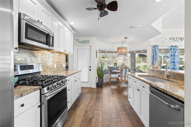 kitchen featuring decorative light fixtures, sink, white cabinetry, and stainless steel appliances