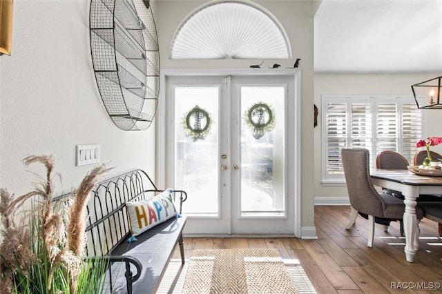 foyer with french doors, light wood-type flooring, and a notable chandelier