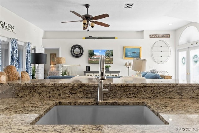 kitchen featuring stone countertops, ceiling fan, and sink