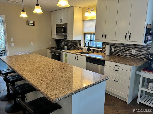 3809 N Seminole Pt, Crystal River, FL 34428 - kitchen with appliances with stainless steel finishes, a sink, backsplash, dark tile patterned floors, and a kitchen breakfast bar