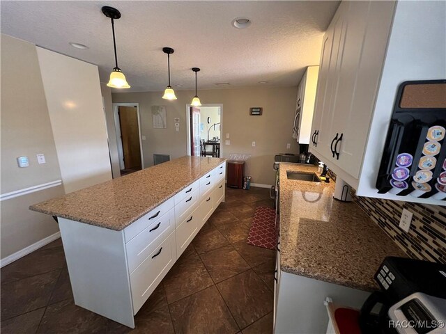 3809 N Seminole Pt, Crystal River, FL 34428 - kitchen with a center island, a sink, white cabinets, light stone counters, and a textured ceiling