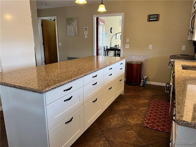 3809 N Seminole Pt, Crystal River, FL 34428 - kitchen featuring light stone counters, baseboards, white cabinetry, decorative light fixtures, and stainless steel microwave