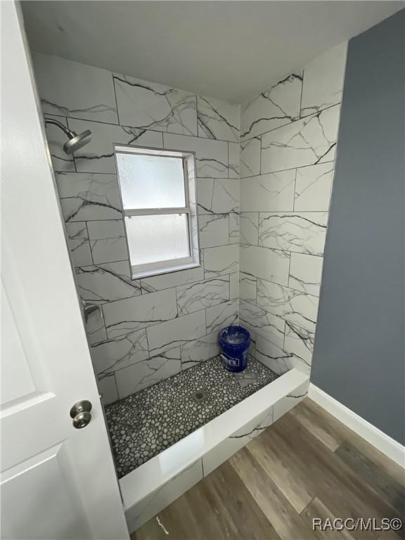 bathroom featuring wood-type flooring and tiled shower