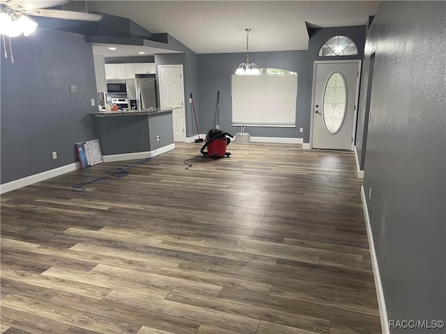 interior space with dark wood-type flooring, stainless steel fridge, vaulted ceiling, and white cabinets