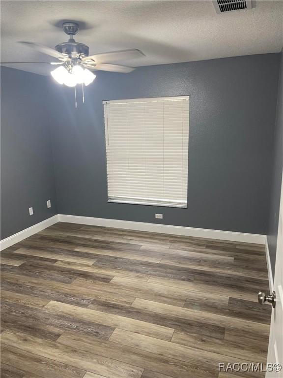 unfurnished room with ceiling fan, wood-type flooring, and a textured ceiling