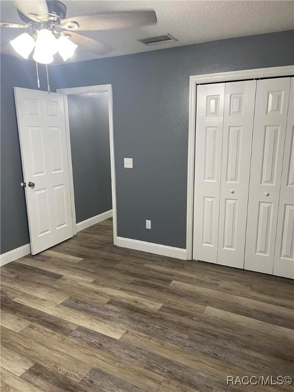 unfurnished bedroom featuring ceiling fan, dark hardwood / wood-style floors, a closet, and a textured ceiling