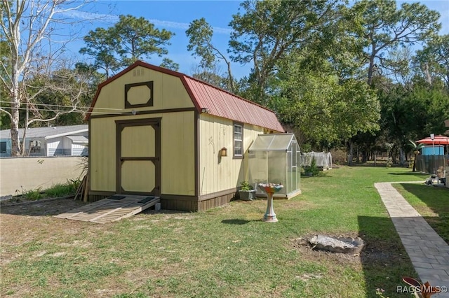 view of greenhouse with a storage shed, fence, and a lawn