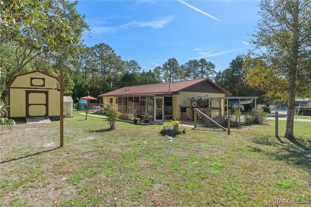 rear view of house featuring an outbuilding, a storage unit, a lawn, and a sunroom