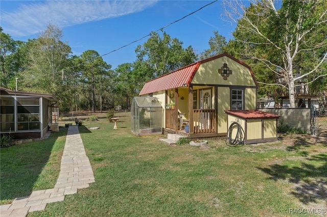 exterior space featuring a lawn, a gambrel roof, metal roof, an exterior structure, and an outdoor structure