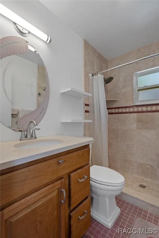 bathroom with toilet, tile patterned floors, a tile shower, and vanity