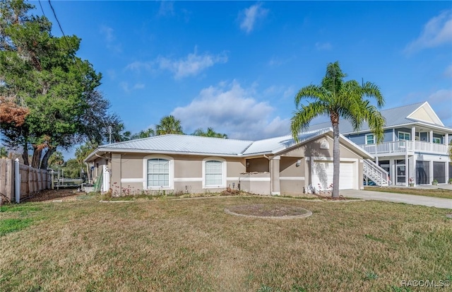 view of front of home with stucco siding, concrete driveway, fence, a garage, and a front lawn