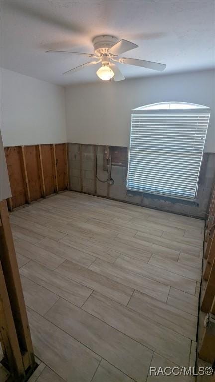 unfurnished room featuring wood tiled floor, wainscoting, and ceiling fan