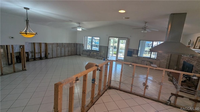 empty room featuring light tile patterned floors, vaulted ceiling, a ceiling fan, and wainscoting