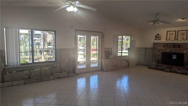 unfurnished living room with ceiling fan, light tile patterned floors, a brick fireplace, and lofted ceiling