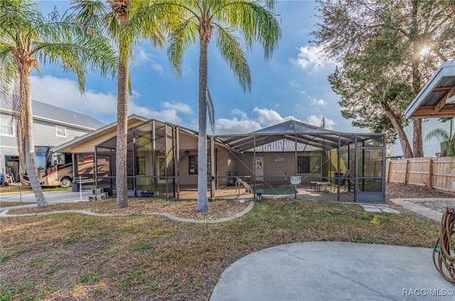 view of yard with glass enclosure, a patio, fence, and a fenced in pool