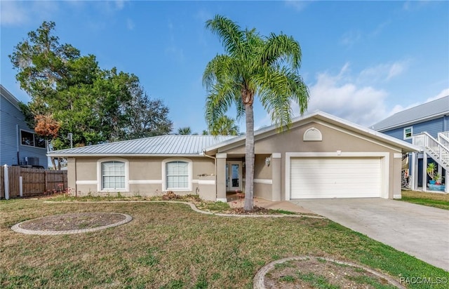 ranch-style house with an attached garage, metal roof, a front lawn, and stucco siding