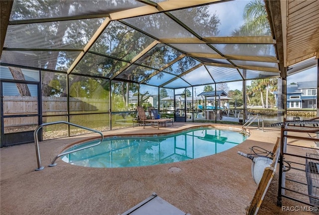 pool featuring a lanai, a patio area, and fence