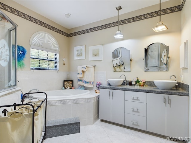 bathroom featuring tile patterned flooring, vanity, and a relaxing tiled tub