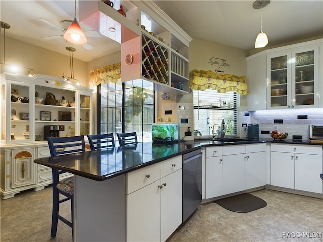 kitchen featuring stainless steel dishwasher, sink, pendant lighting, white cabinetry, and a breakfast bar area