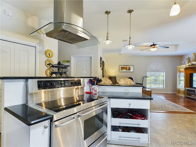 kitchen with light wood-type flooring, stainless steel range with electric stovetop, island range hood, ceiling fan, and pendant lighting