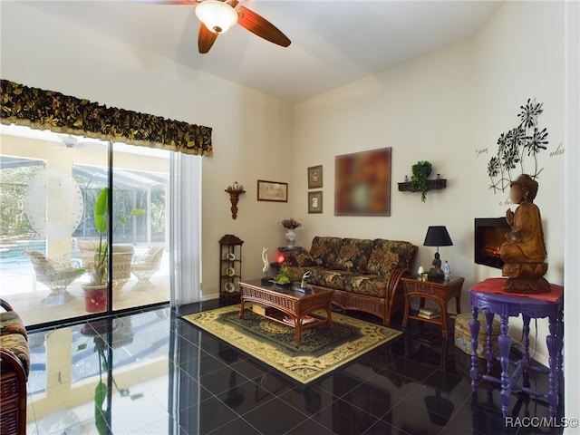 living room featuring ceiling fan and dark tile patterned flooring