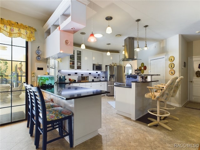 kitchen featuring kitchen peninsula, appliances with stainless steel finishes, island range hood, decorative light fixtures, and white cabinets