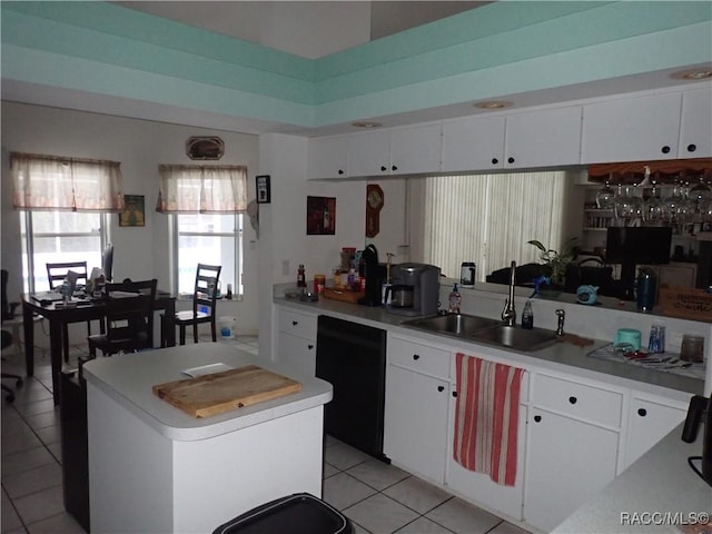 kitchen with a kitchen island, light countertops, black dishwasher, light tile patterned floors, and a sink